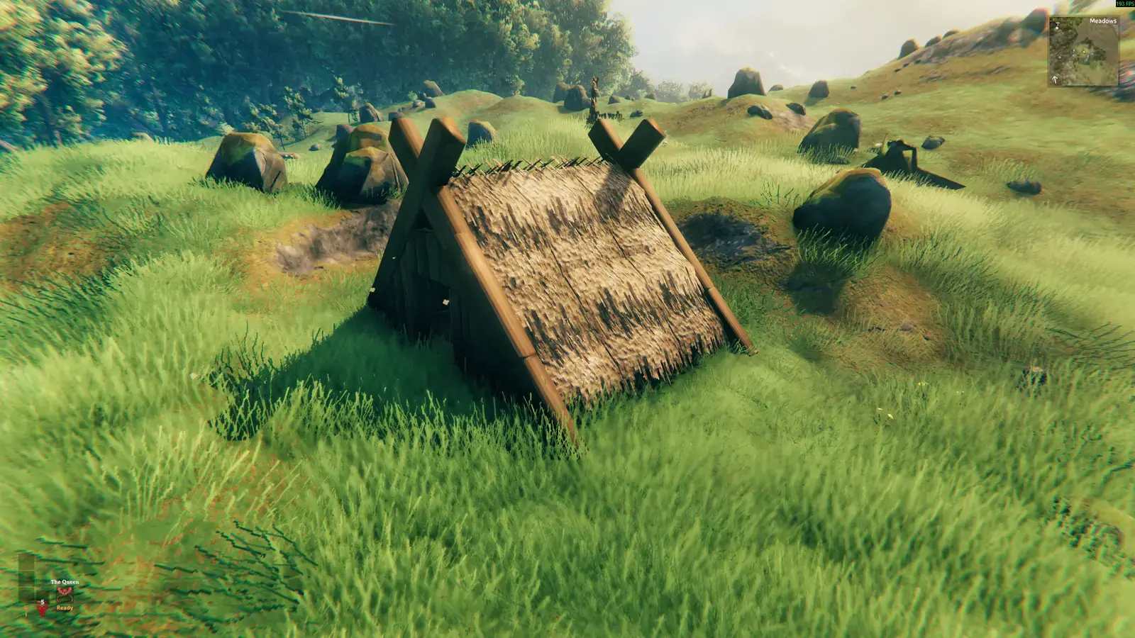 Tiny thatched lean-to standing alone in a sunny Meadows field.