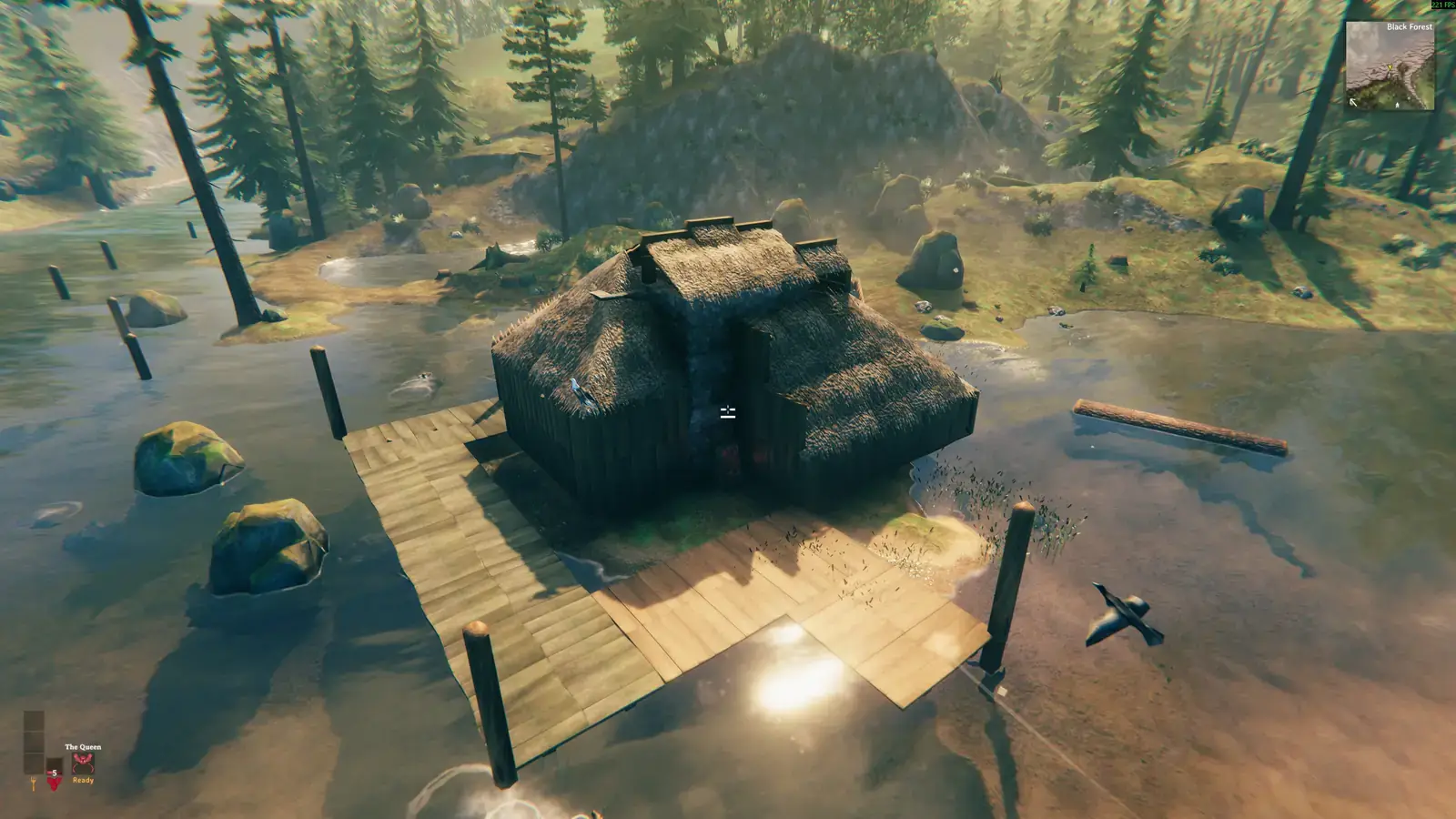 Overhead view of a small coastal hut on a sandy shore beside scattered posts.