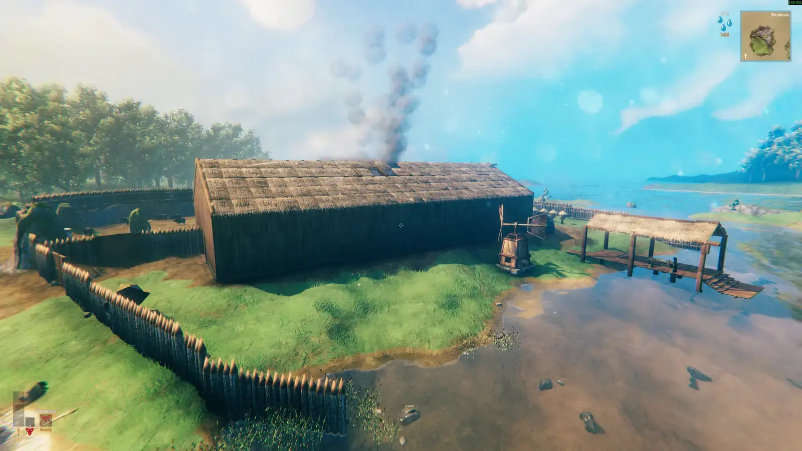 Long thatched house near the coast with smoke rising from the roof.