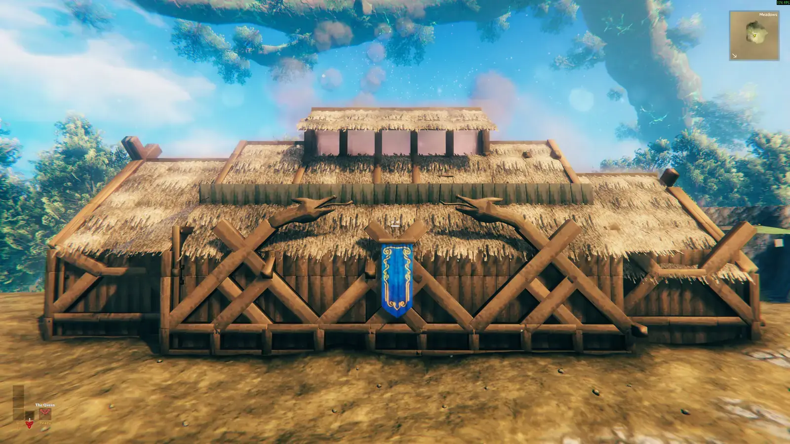Symmetrical thatched longhouse with a blue banner over the front entrance.